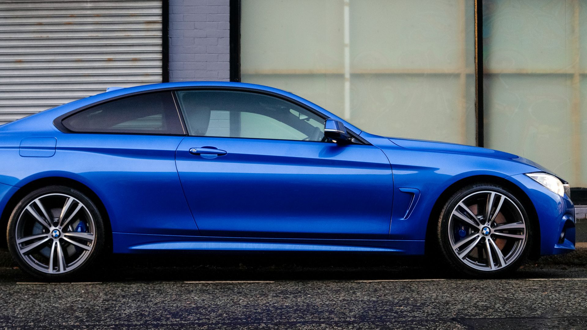 blue coupe beside gray house