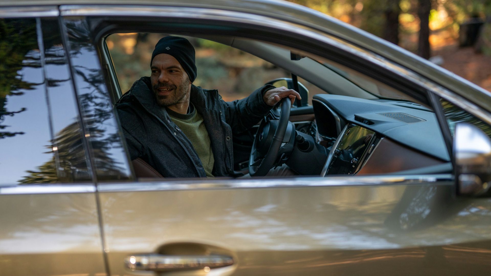 A man sitting in a car holding a steering wheel