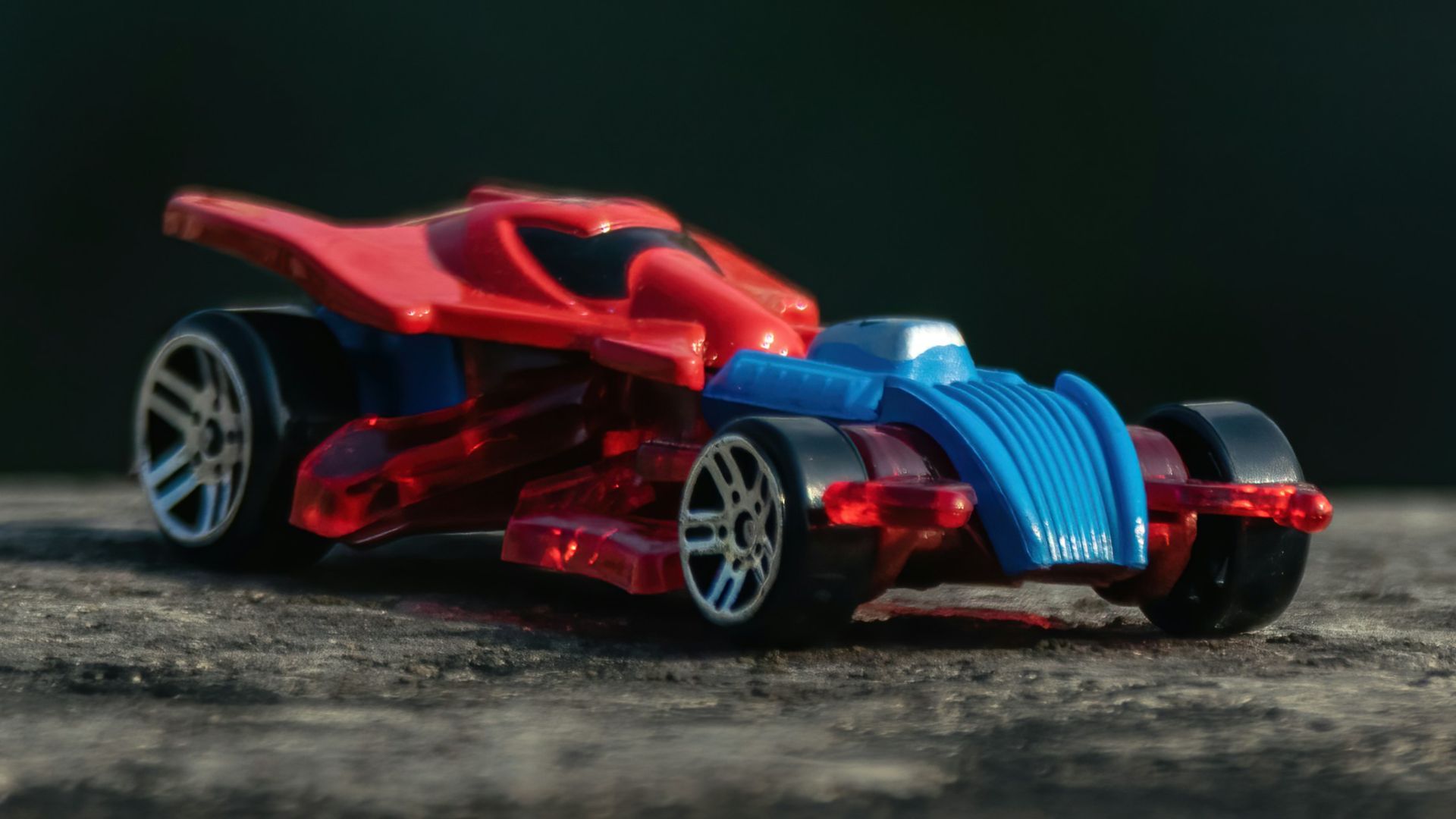 a red and blue toy car sitting on top of a wooden table