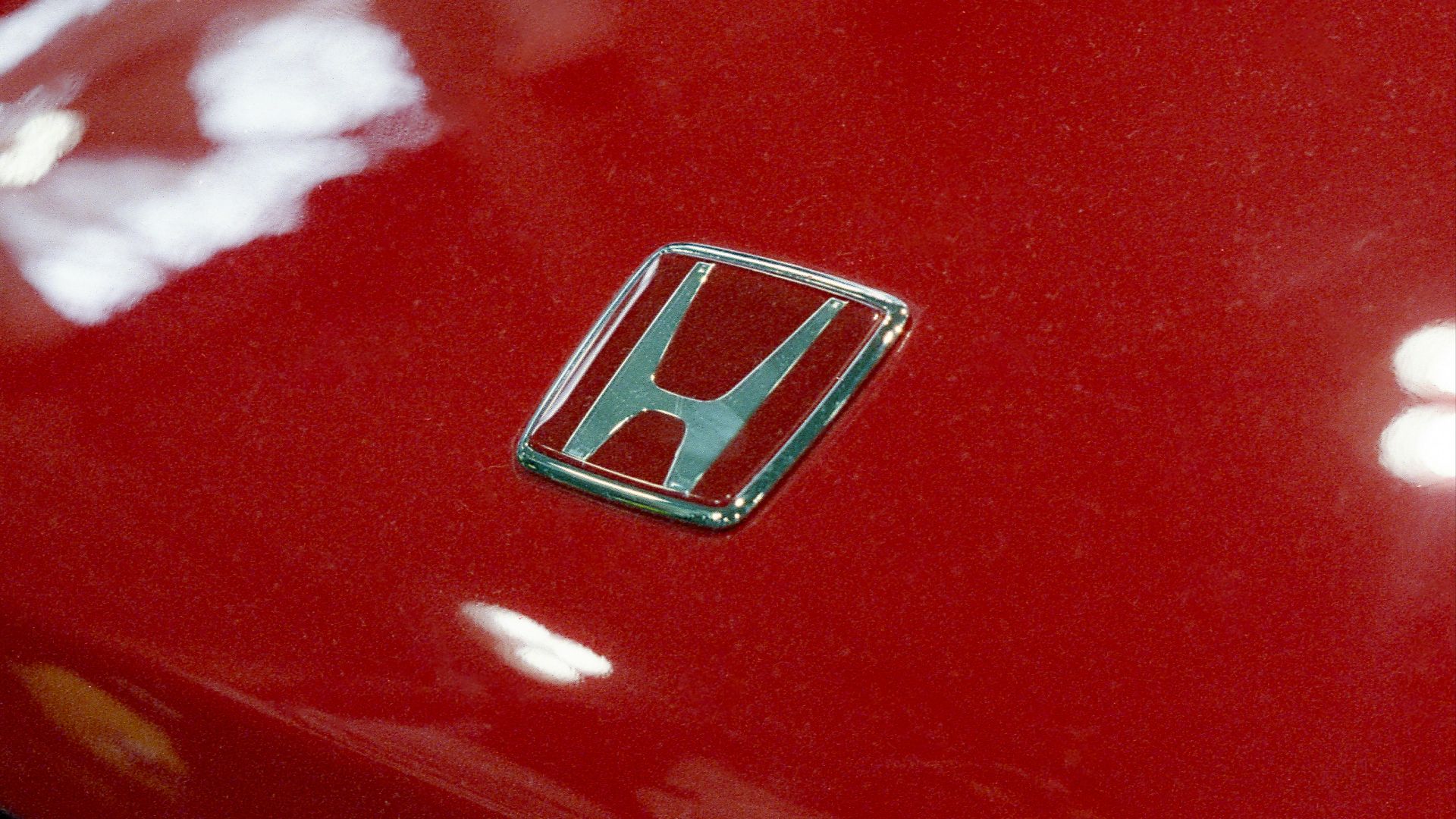 Close-up of a red honda car emblem.