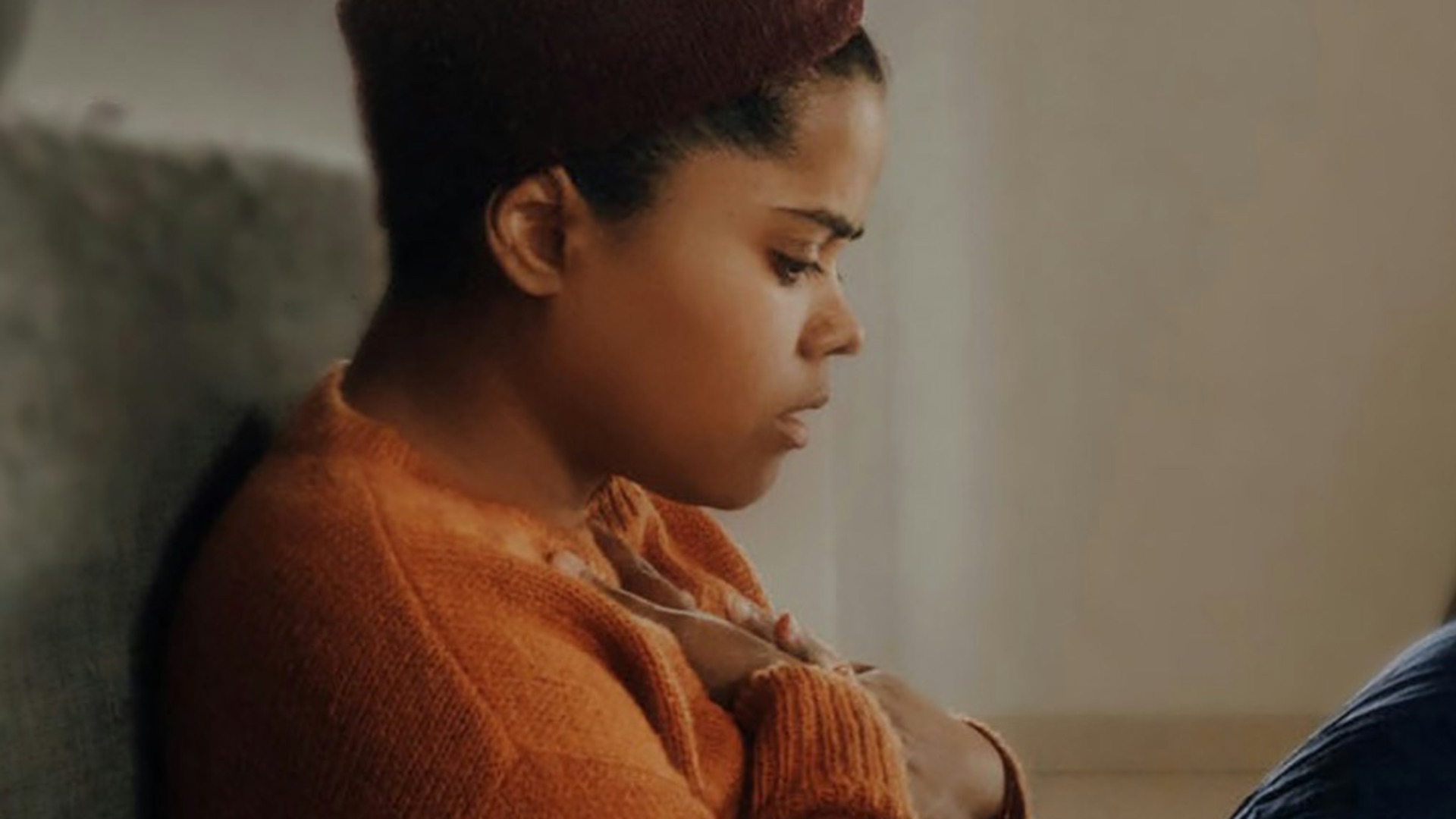 man in orange long sleeve shirt sitting on gray couch