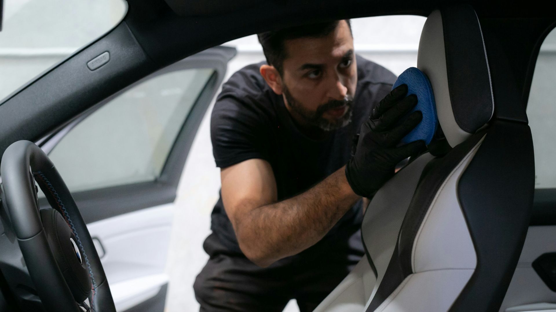 A man cleans a car seat inside the vehicle.
