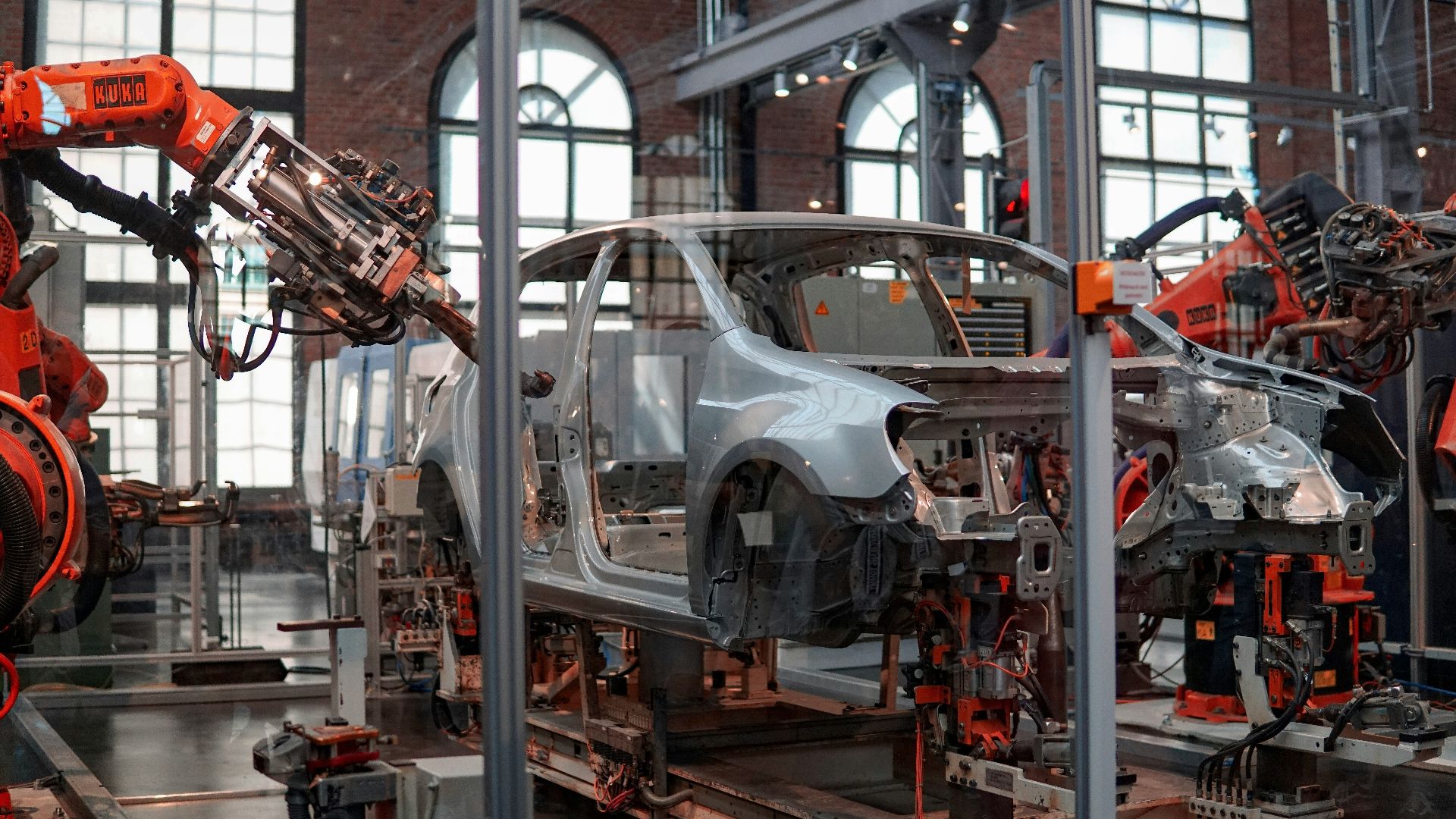 gray vehicle being fixed inside factory using robot machines