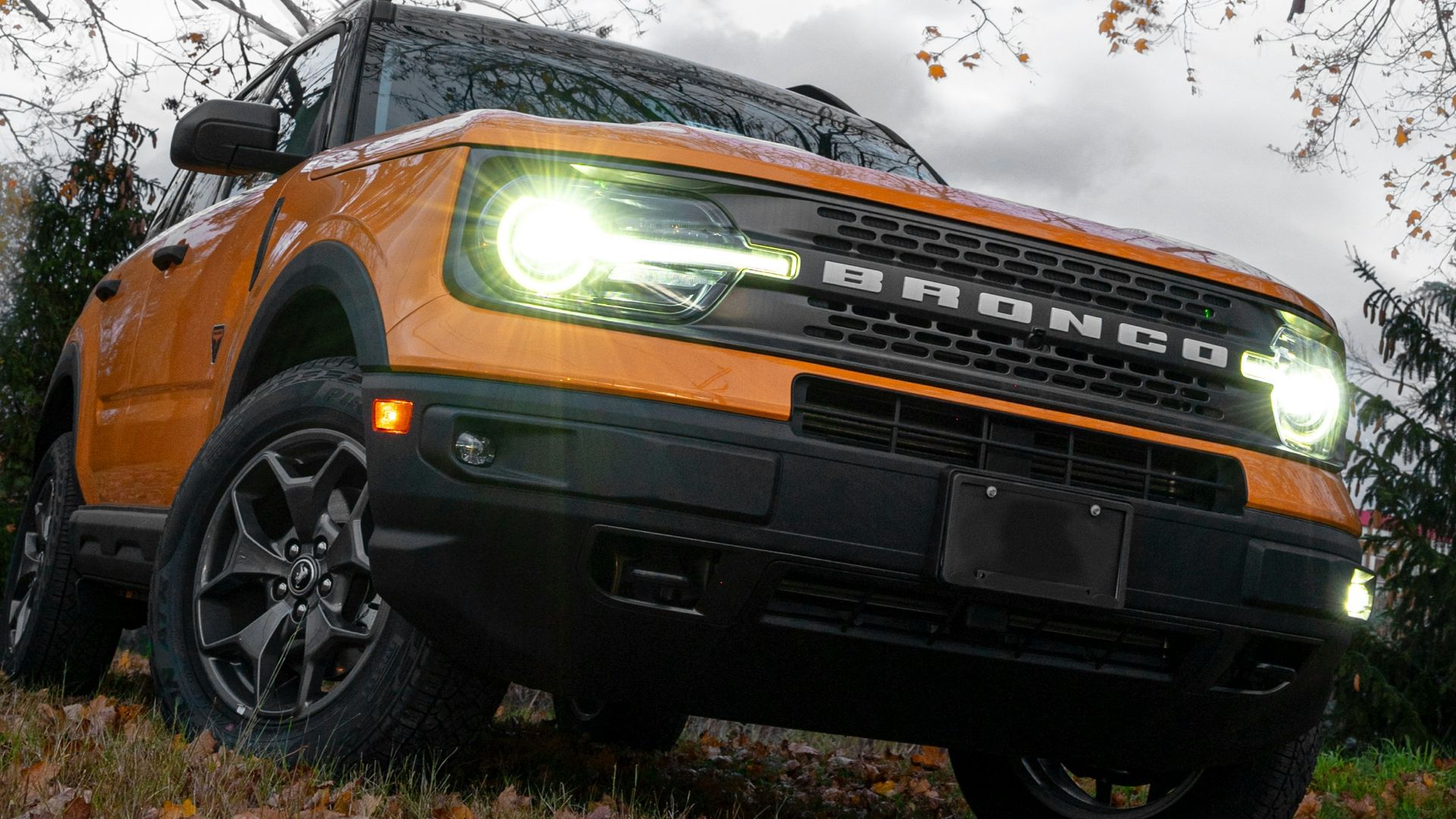a bright orange truck is parked under a tree
