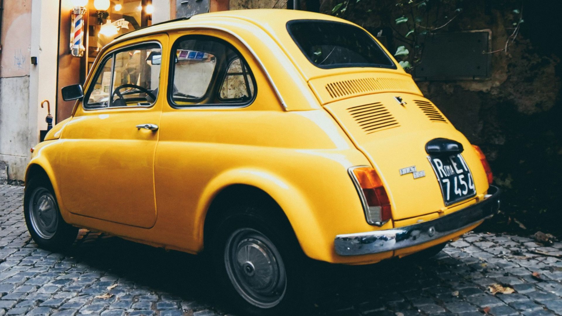 yellow 3-door hatchback parked outside a building