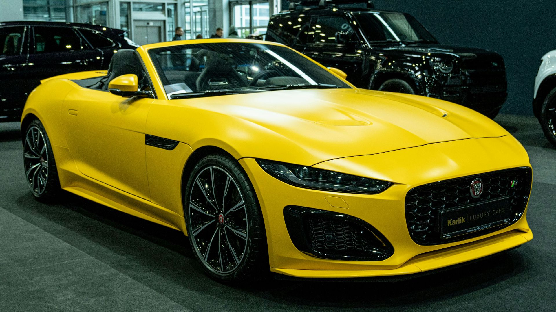 A yellow sports car in a showroom with other cars
