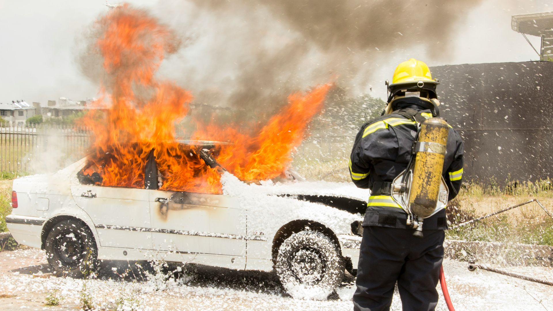 firefighter fighting burning car
