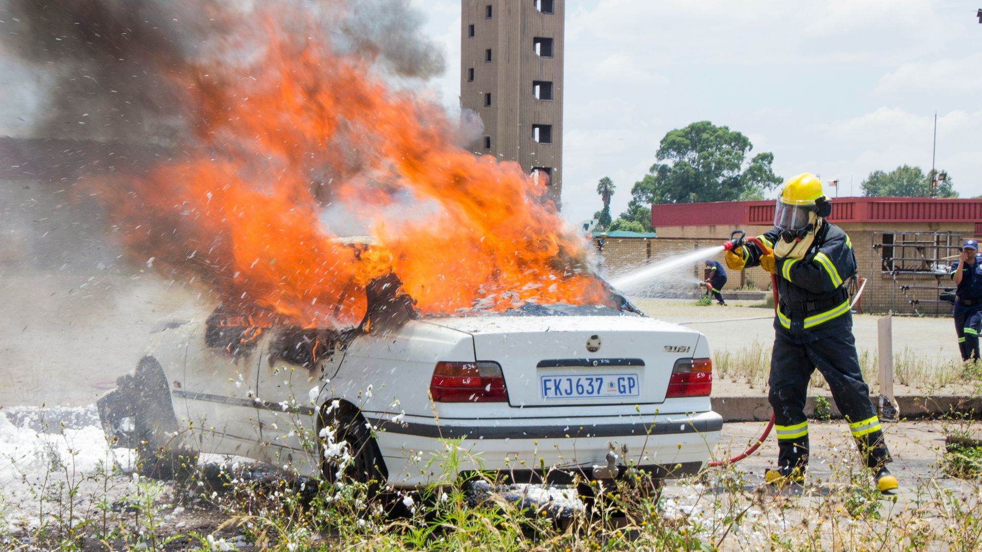 man in yellow jacket standing near white car