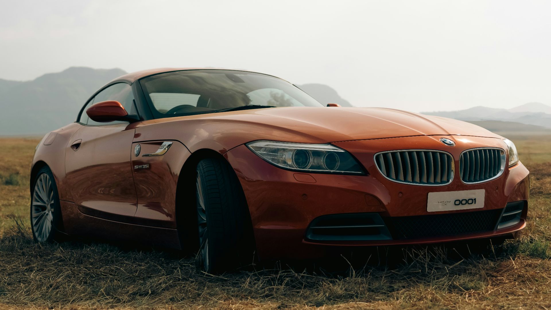 a car parked in a field with mountains in the background