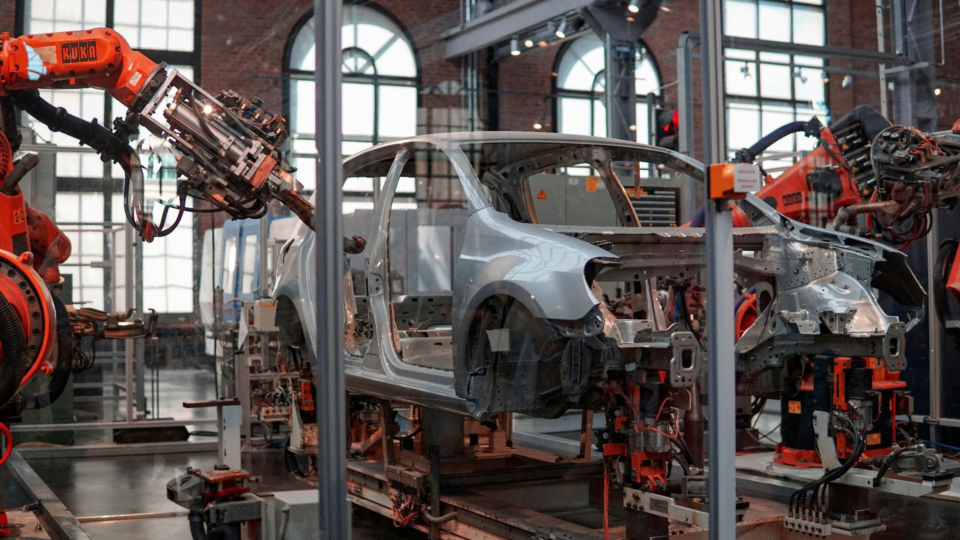 gray vehicle being fixed inside factory using robot machines