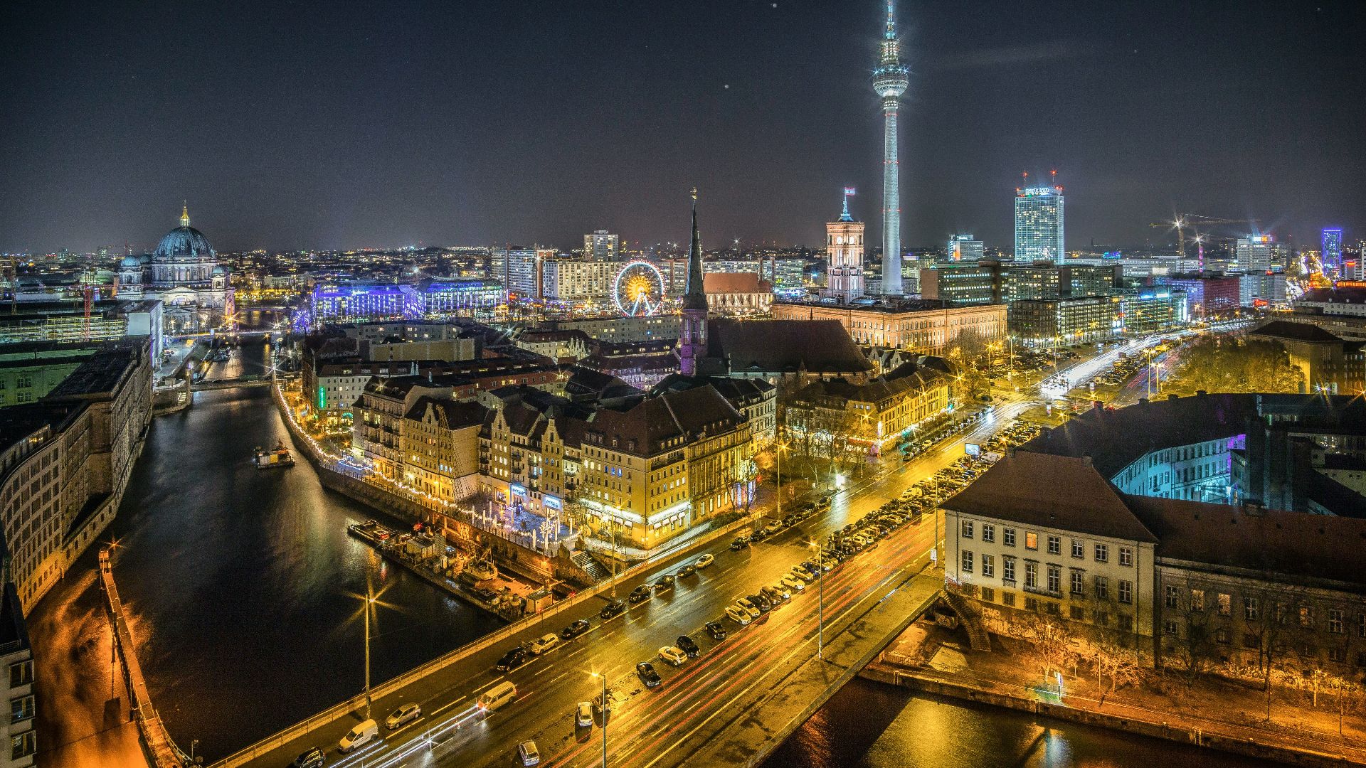 time-lapse photography of vehicle at the road in between the building at nighttime aerial photography