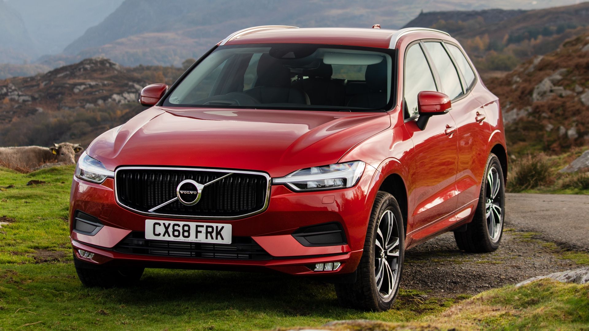 red Volvo SUV parking on green field