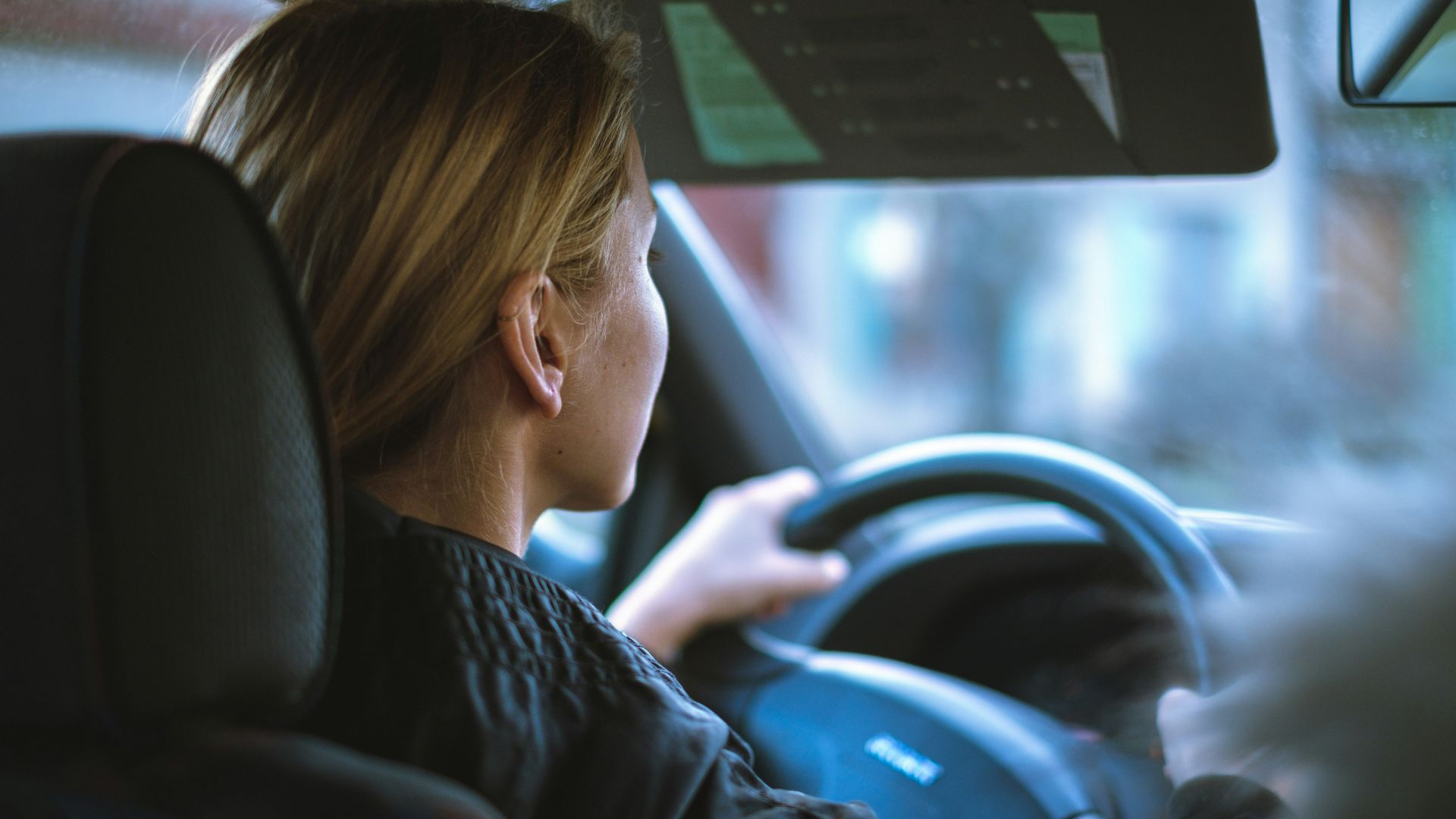 a woman sitting in a car with a steering wheel