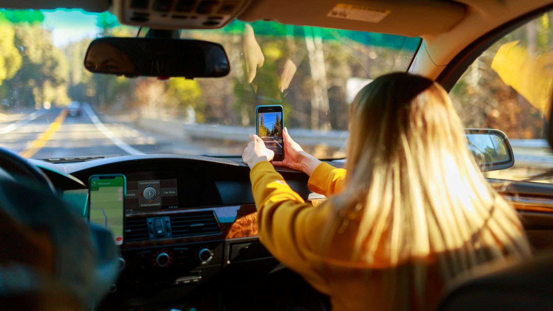 a woman driving a car with a cell phone in her hand