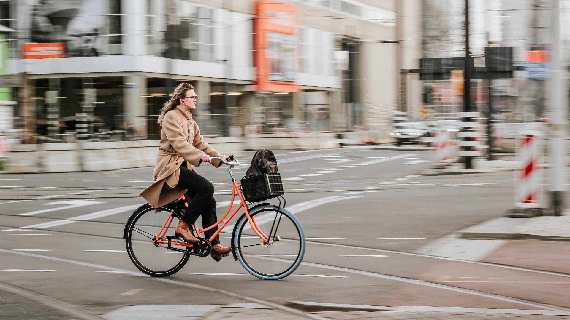 woman in brown coat riding on black bicycle on road during daytime