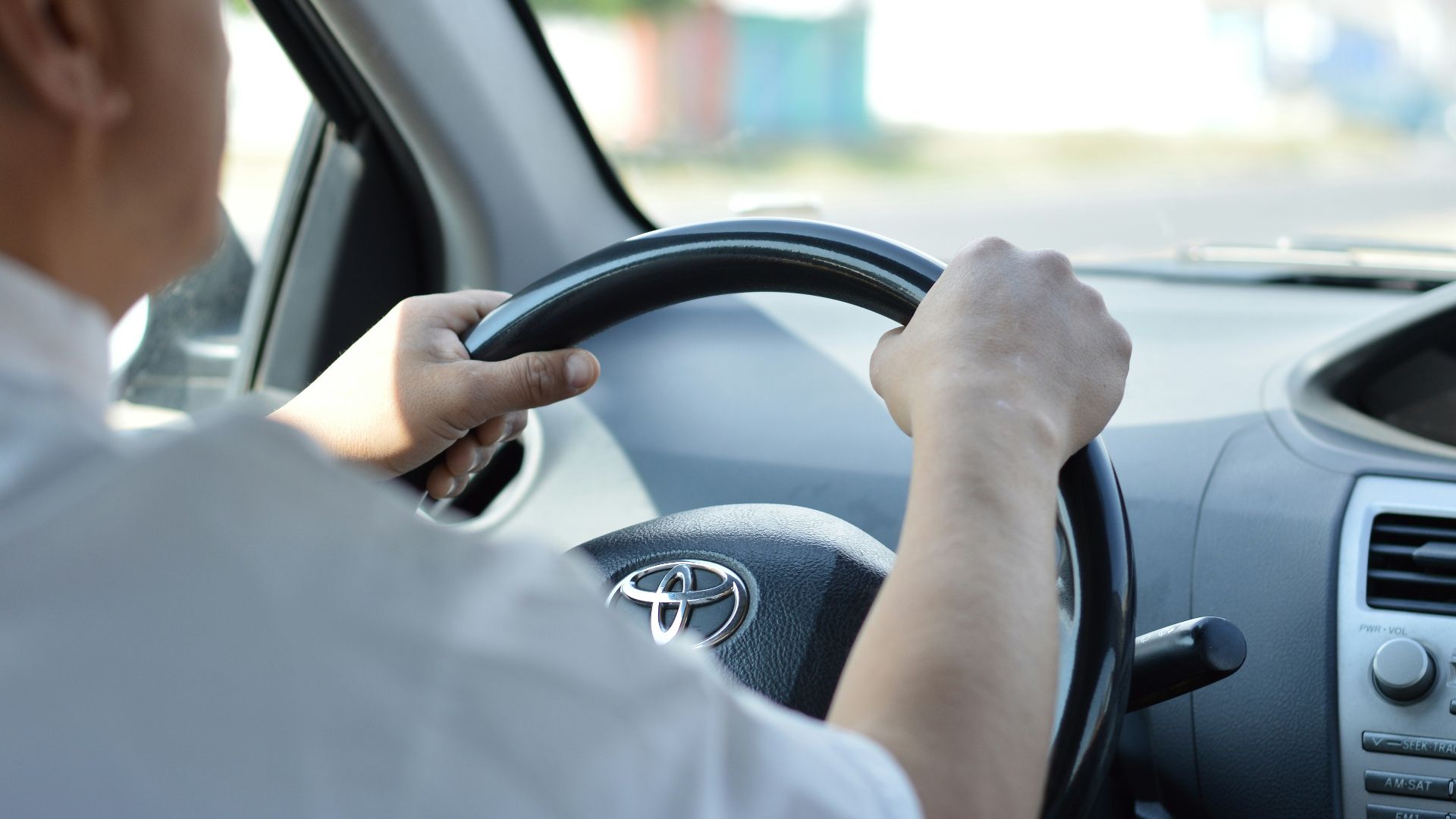 person in white long sleeve shirt driving car