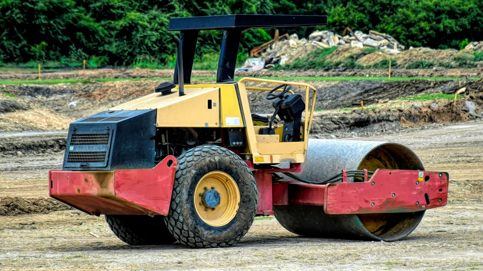 a yellow and red construction vehicle parked on a dirt field