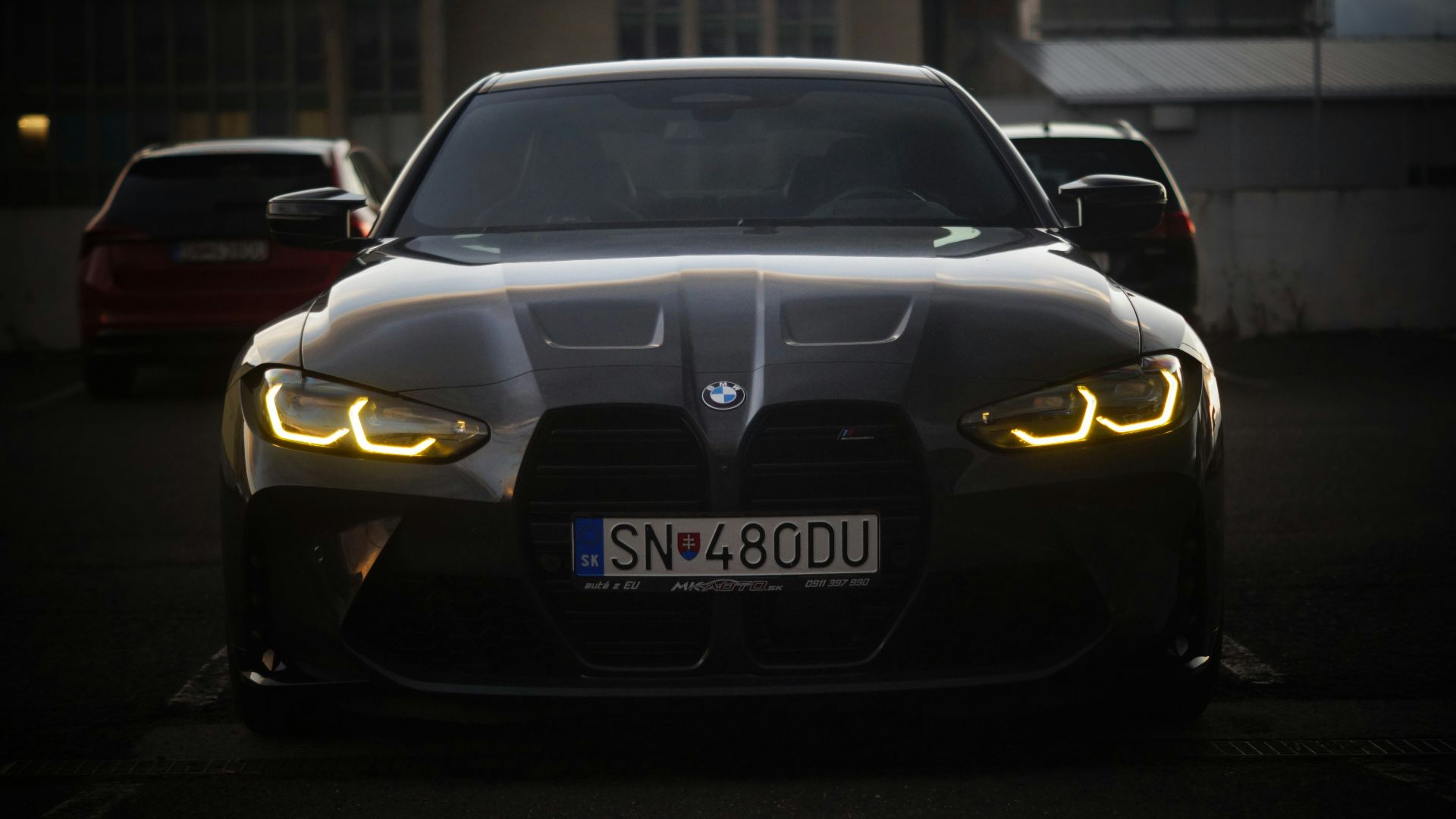 The front of a black car with its lights on