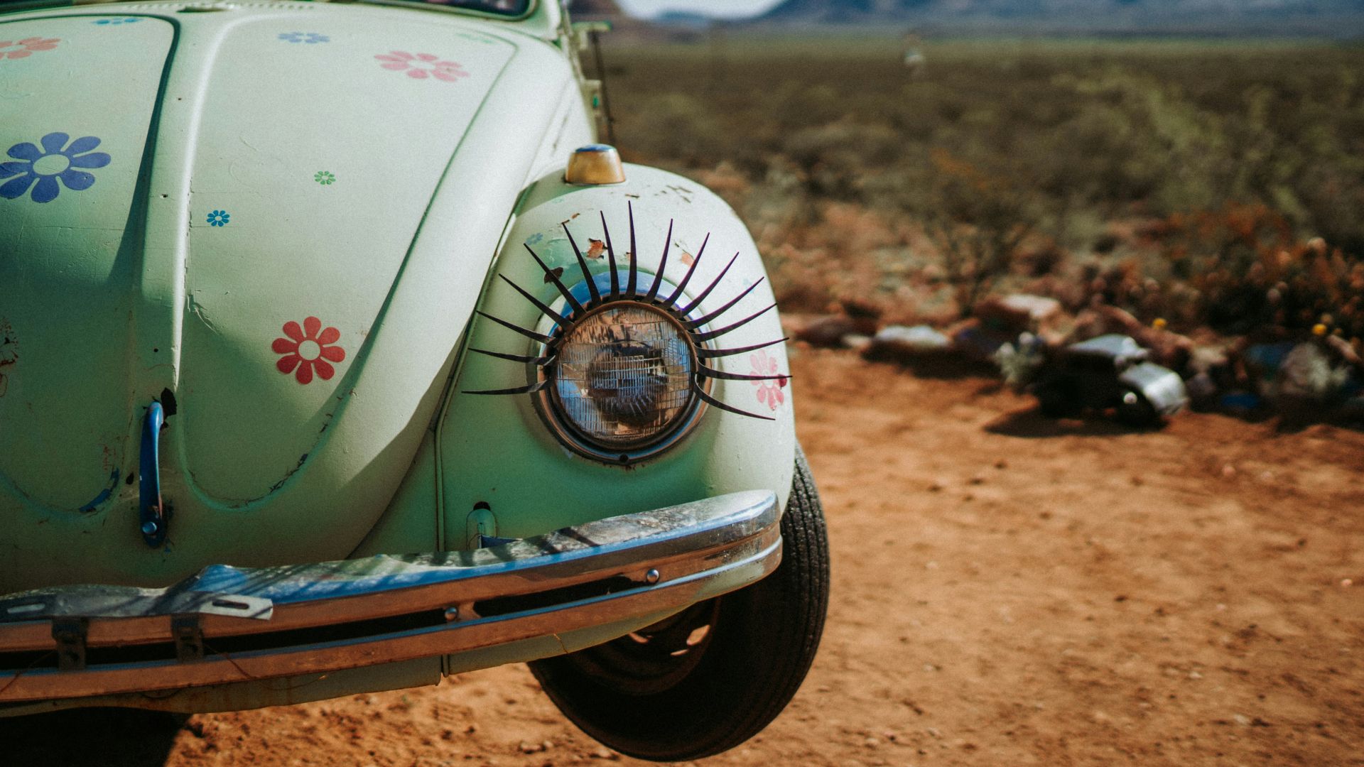 a green car parked on a dirt road