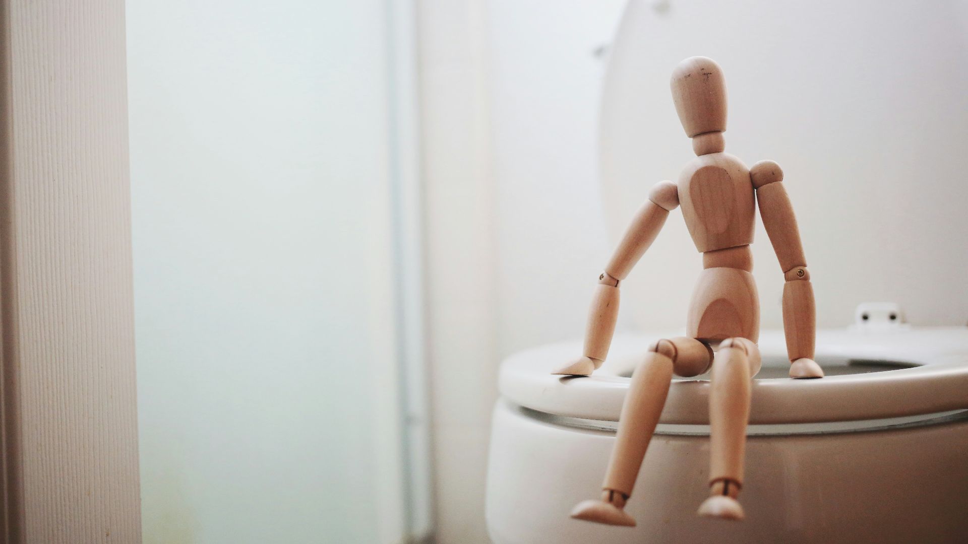 brown wooden doll on white ceramic toilet bowl