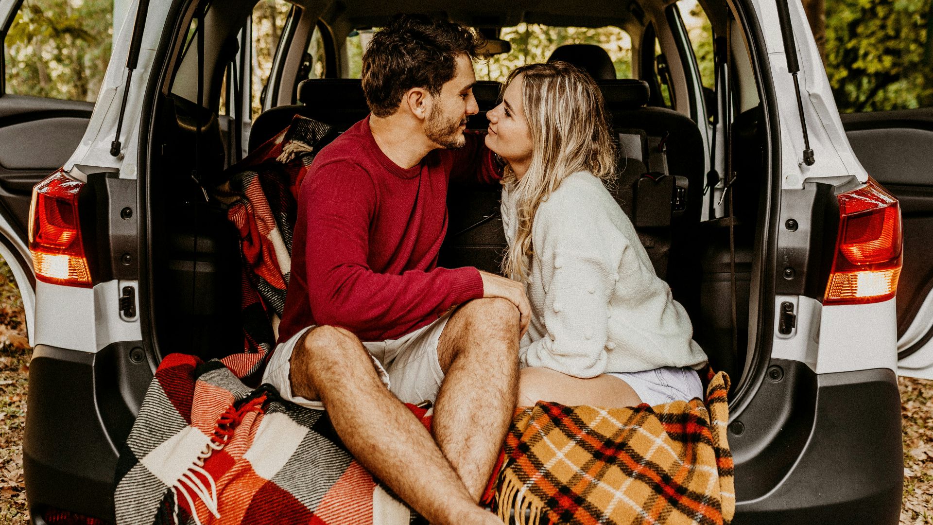 man and woman sitting on car's trunk