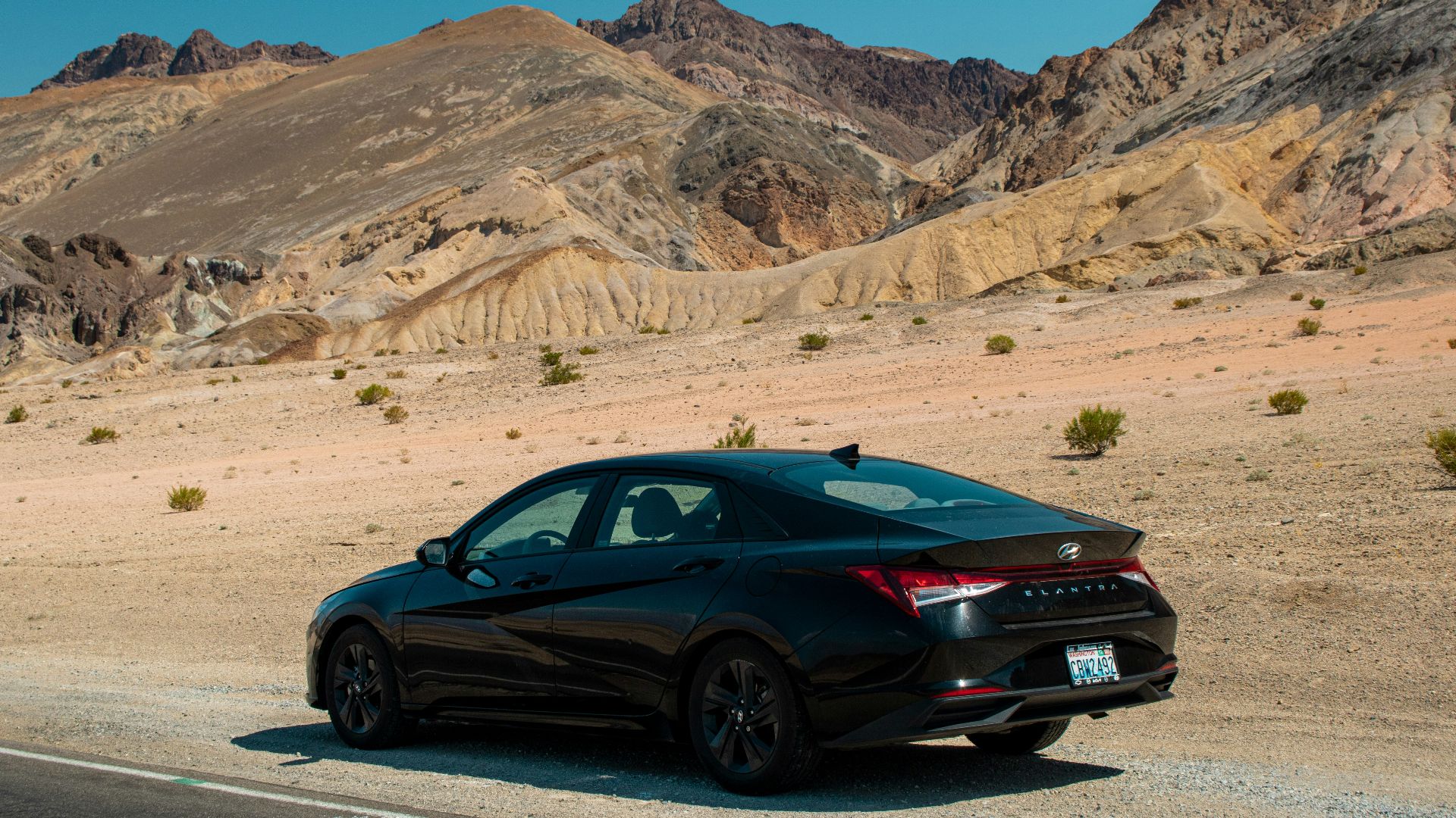 A black car driving down a desert road