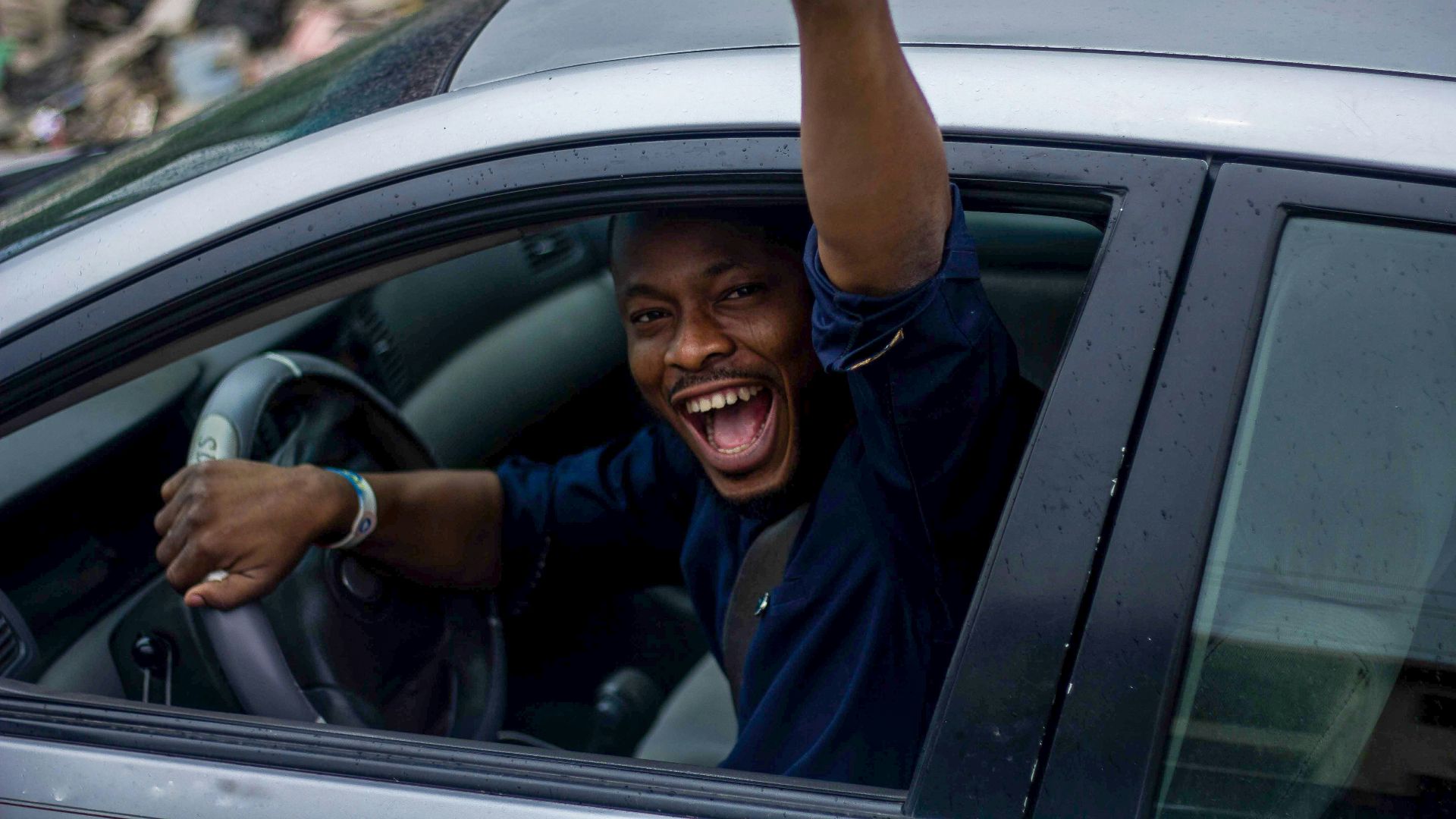 man in black t-shirt and blue denim jeans sitting on car seat