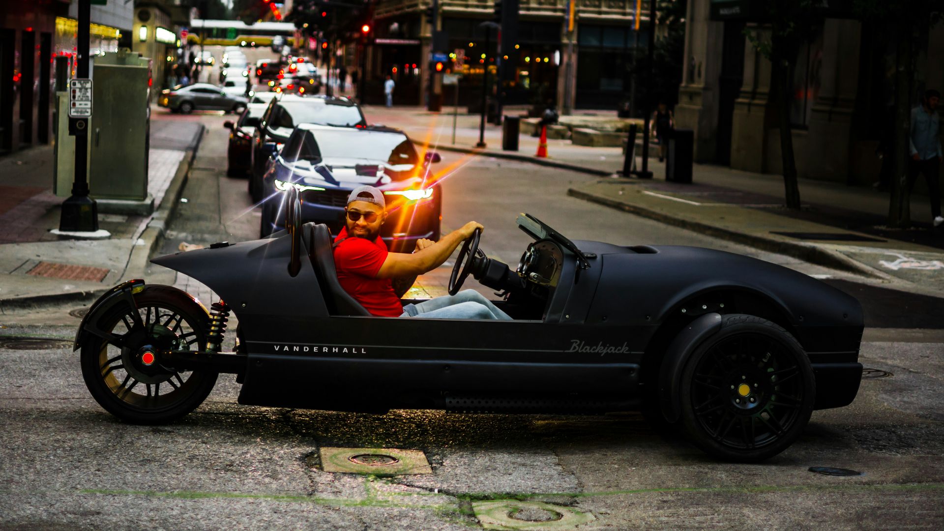 a man driving a car down a street next to tall buildings