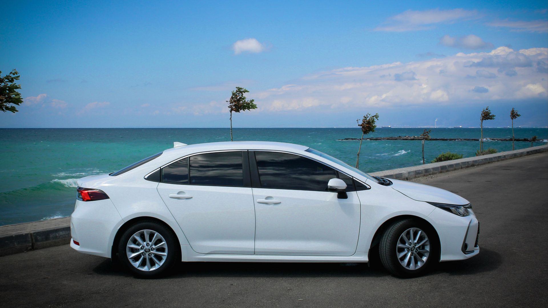 white sedan on gray asphalt road during daytime