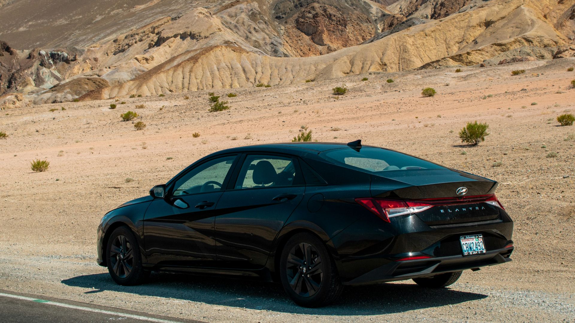 A black car driving down a desert road