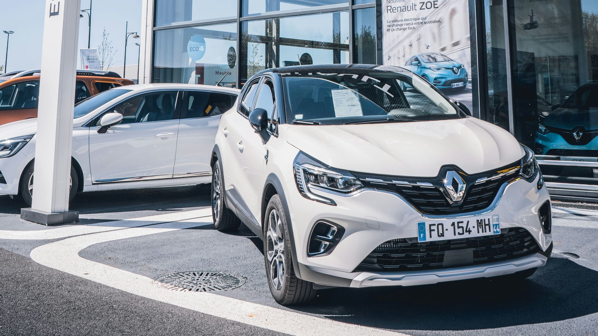 a white car is parked in front of a dealership