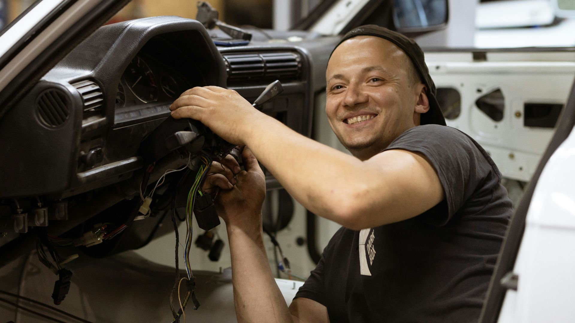 man in black crew neck t-shirt holding black car steering wheel