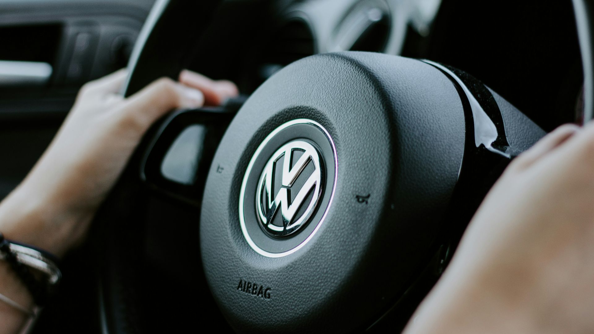 person holding black Volkswagen steering wheel in closed-up photo