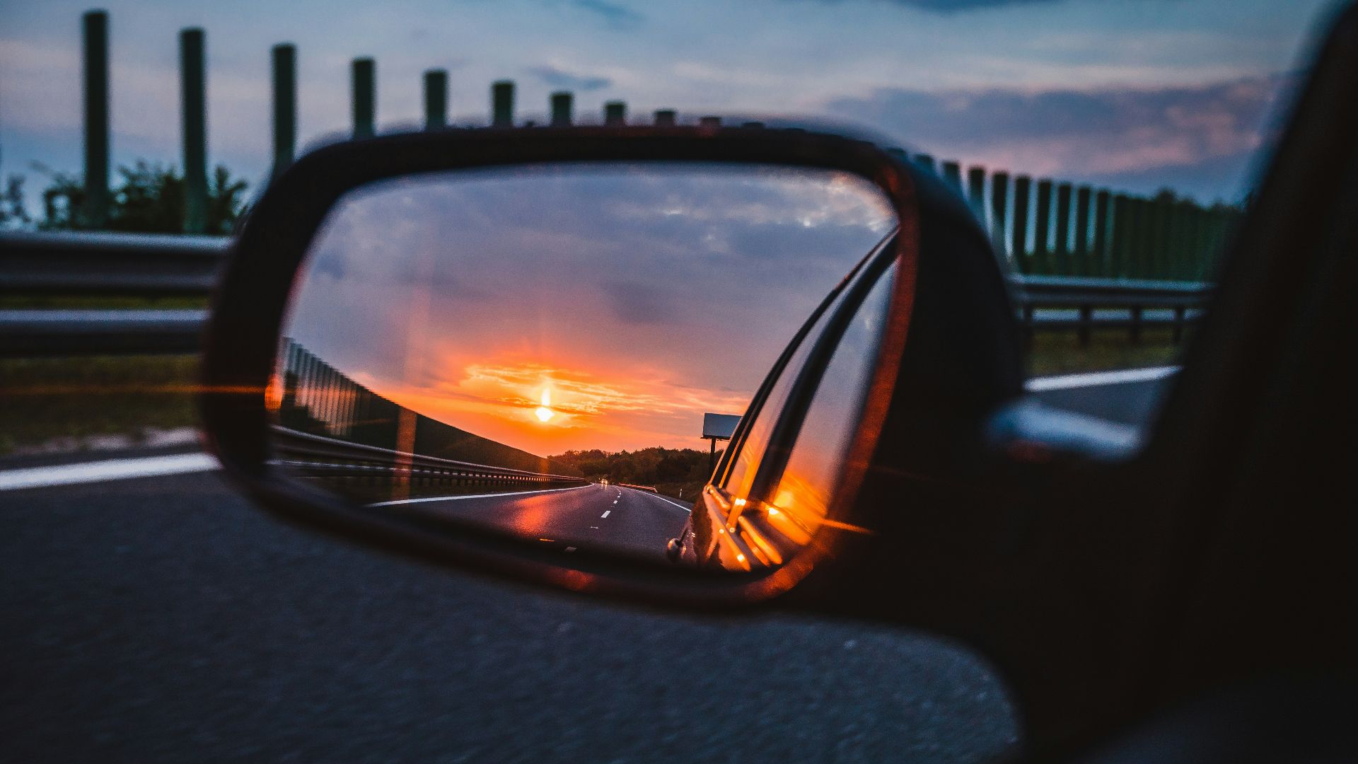 a rear view mirror reflecting a sunset in the side view mirror