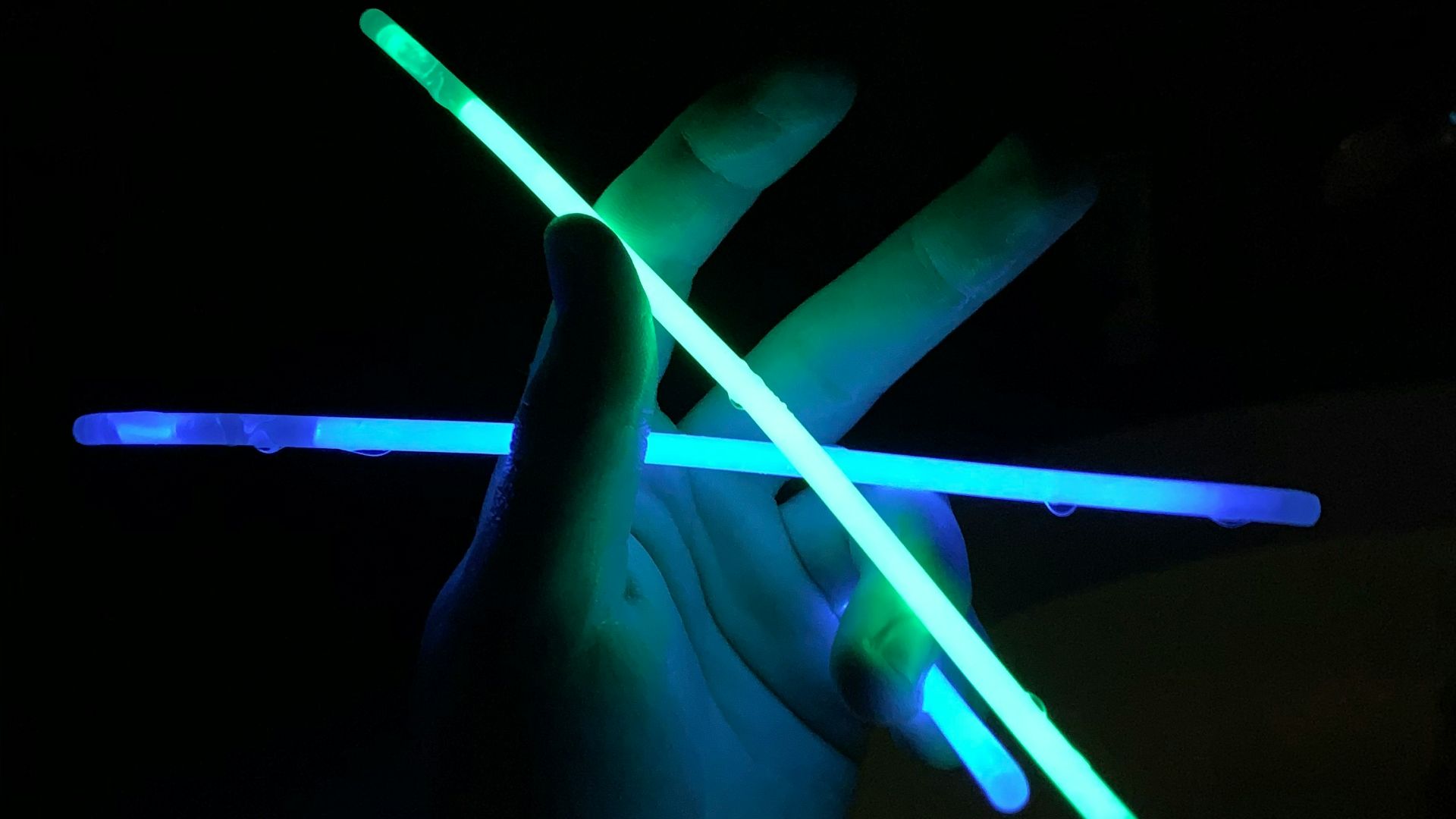 a person holding two glowing sticks in the dark