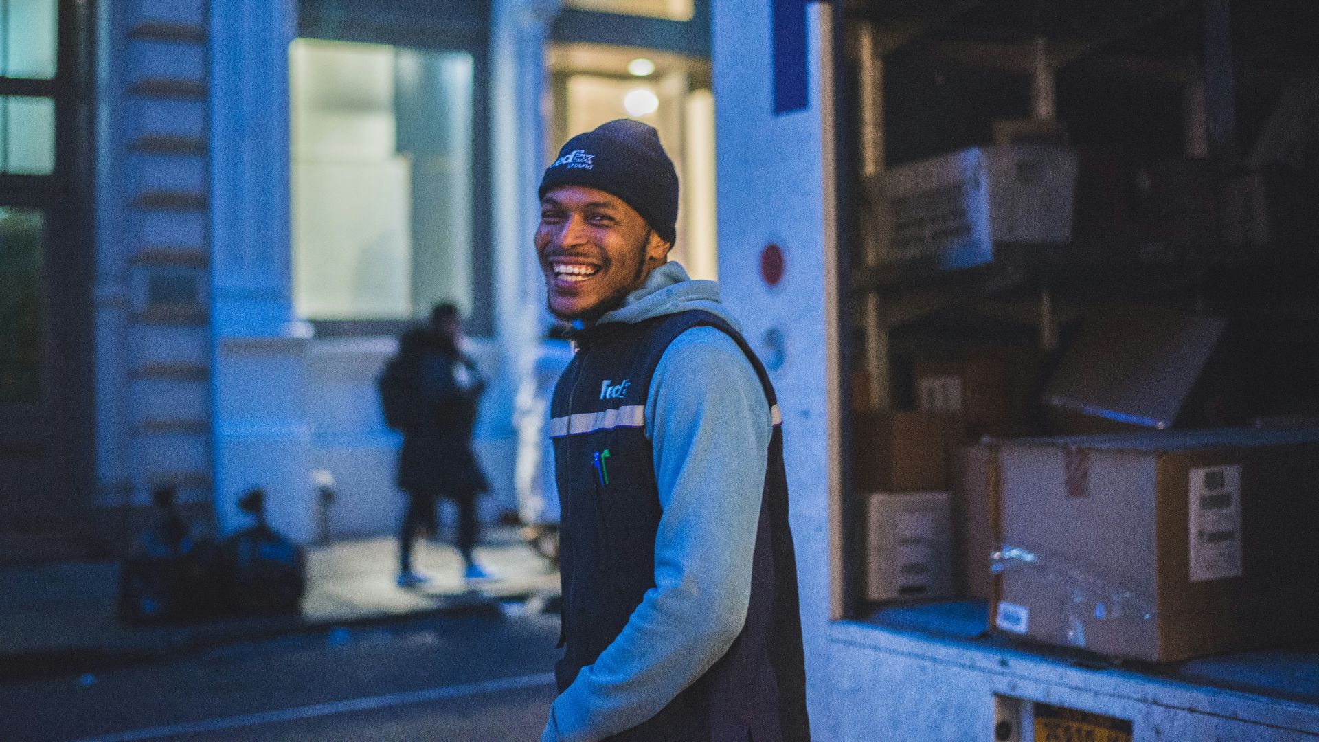 smiling man stands behind delivery truck