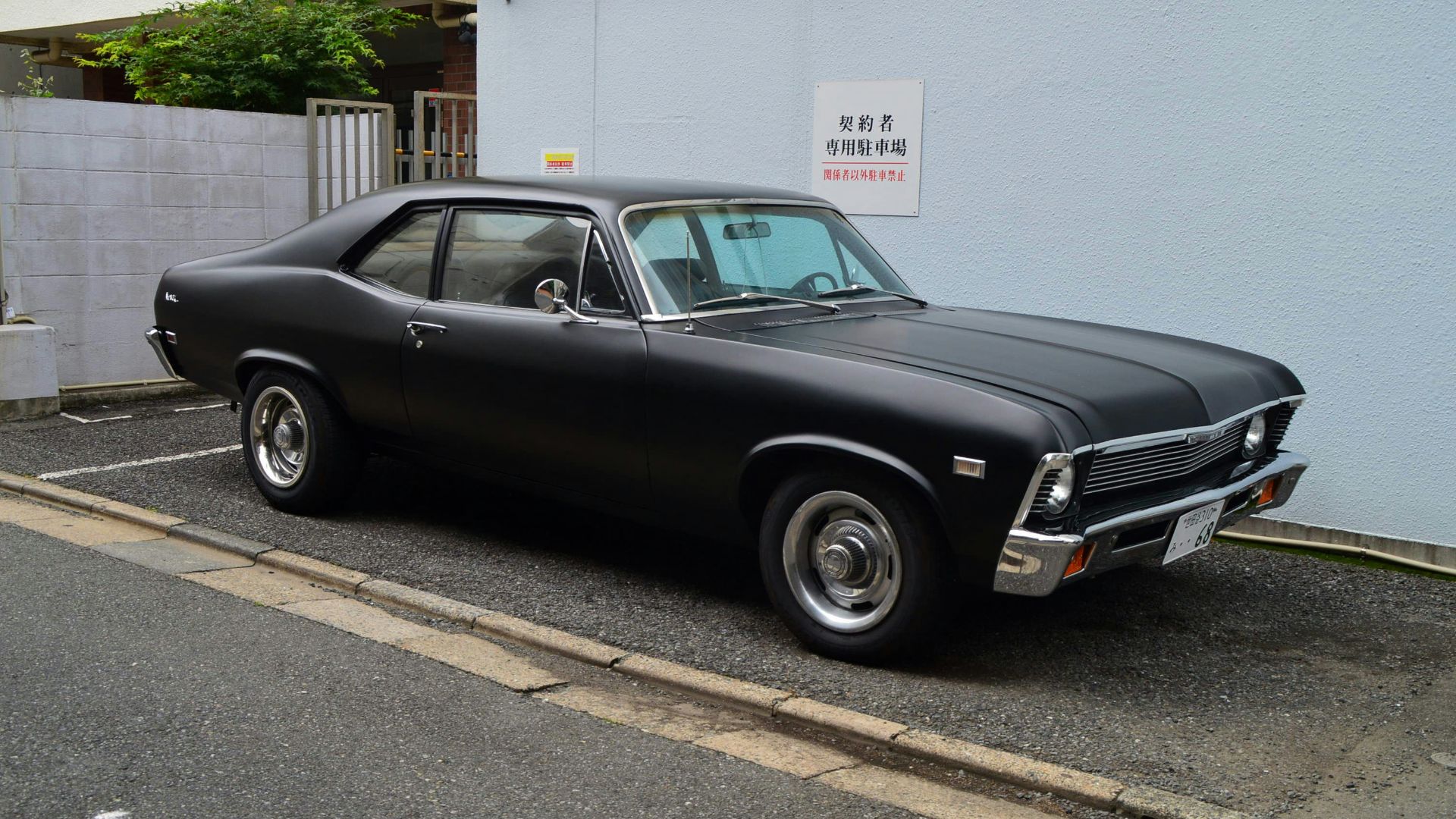 black sedan parked on sidewalk during daytime