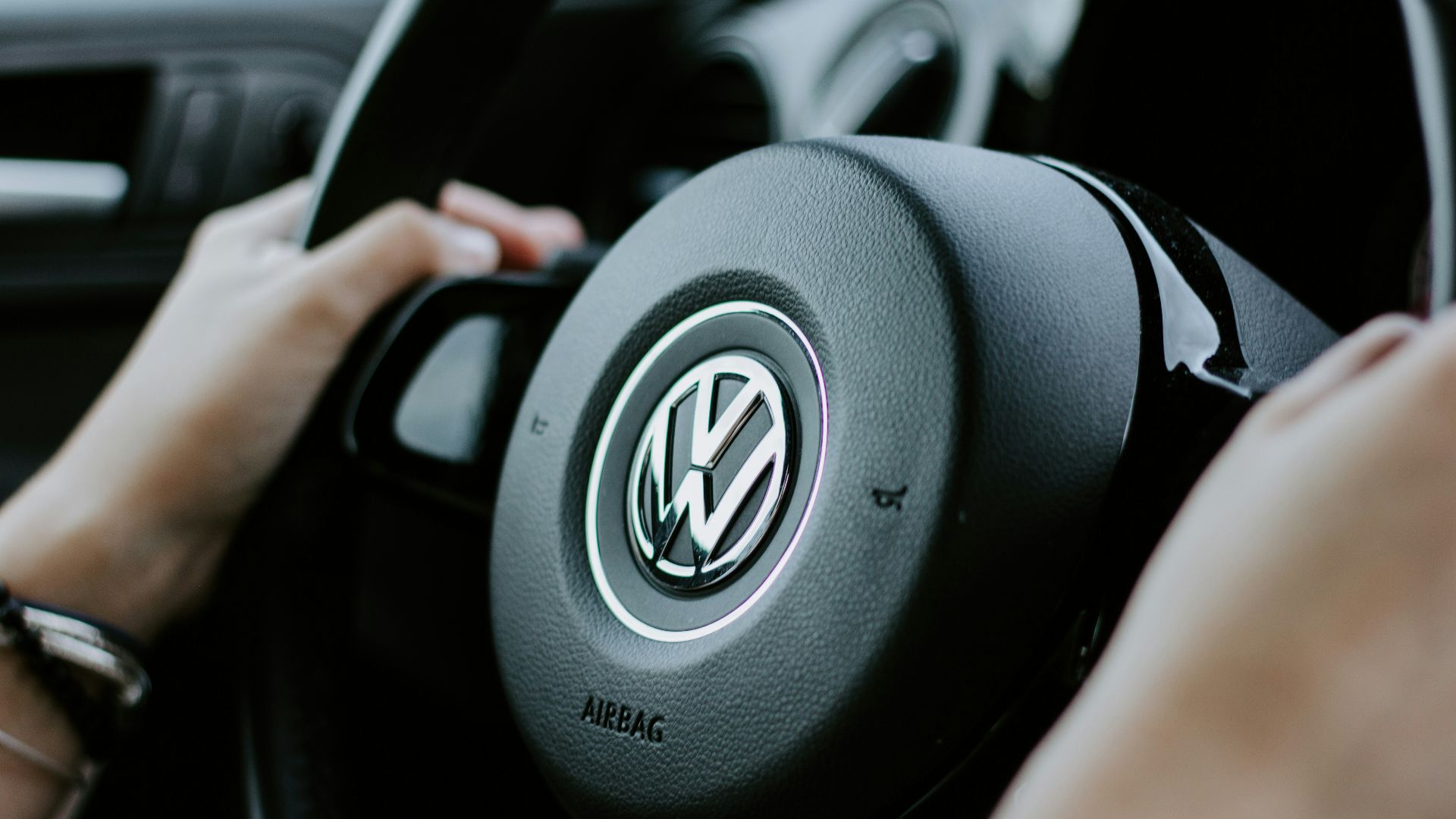 person holding black Volkswagen steering wheel in closed-up photo