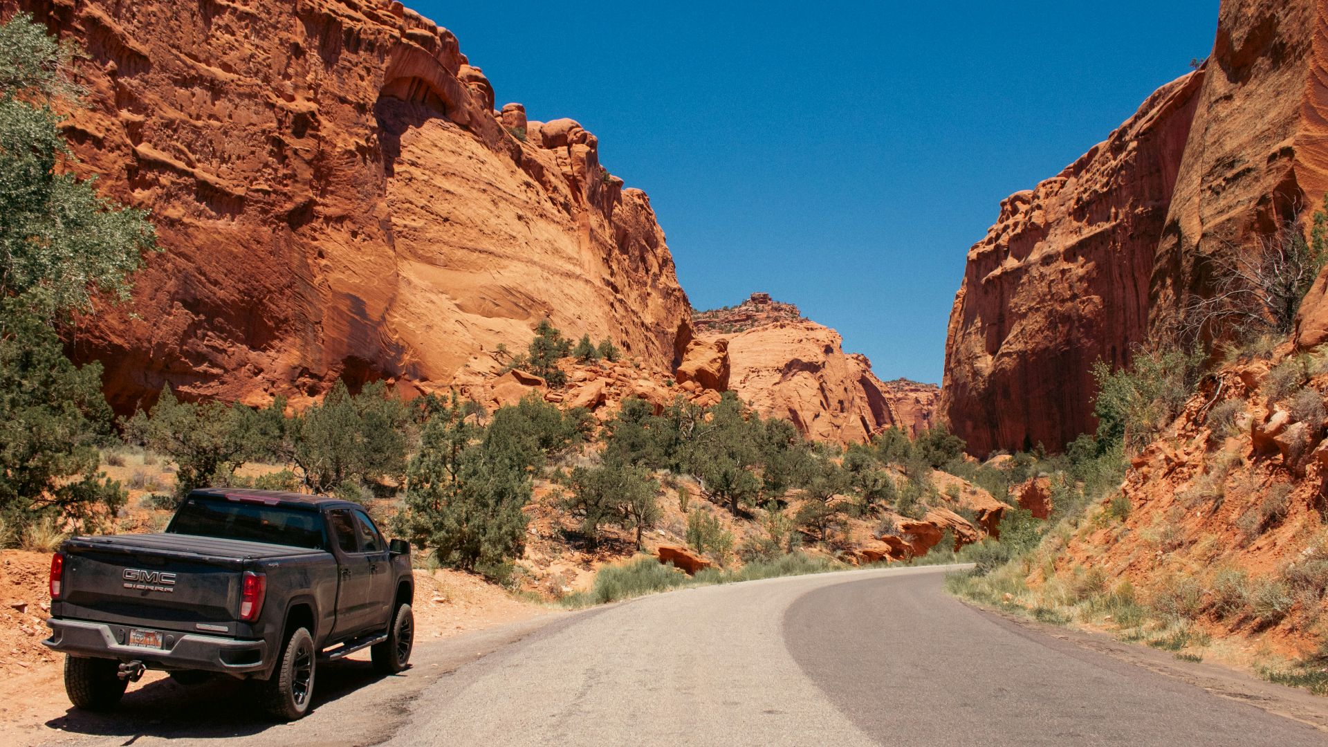 A black truck driving down a desert road