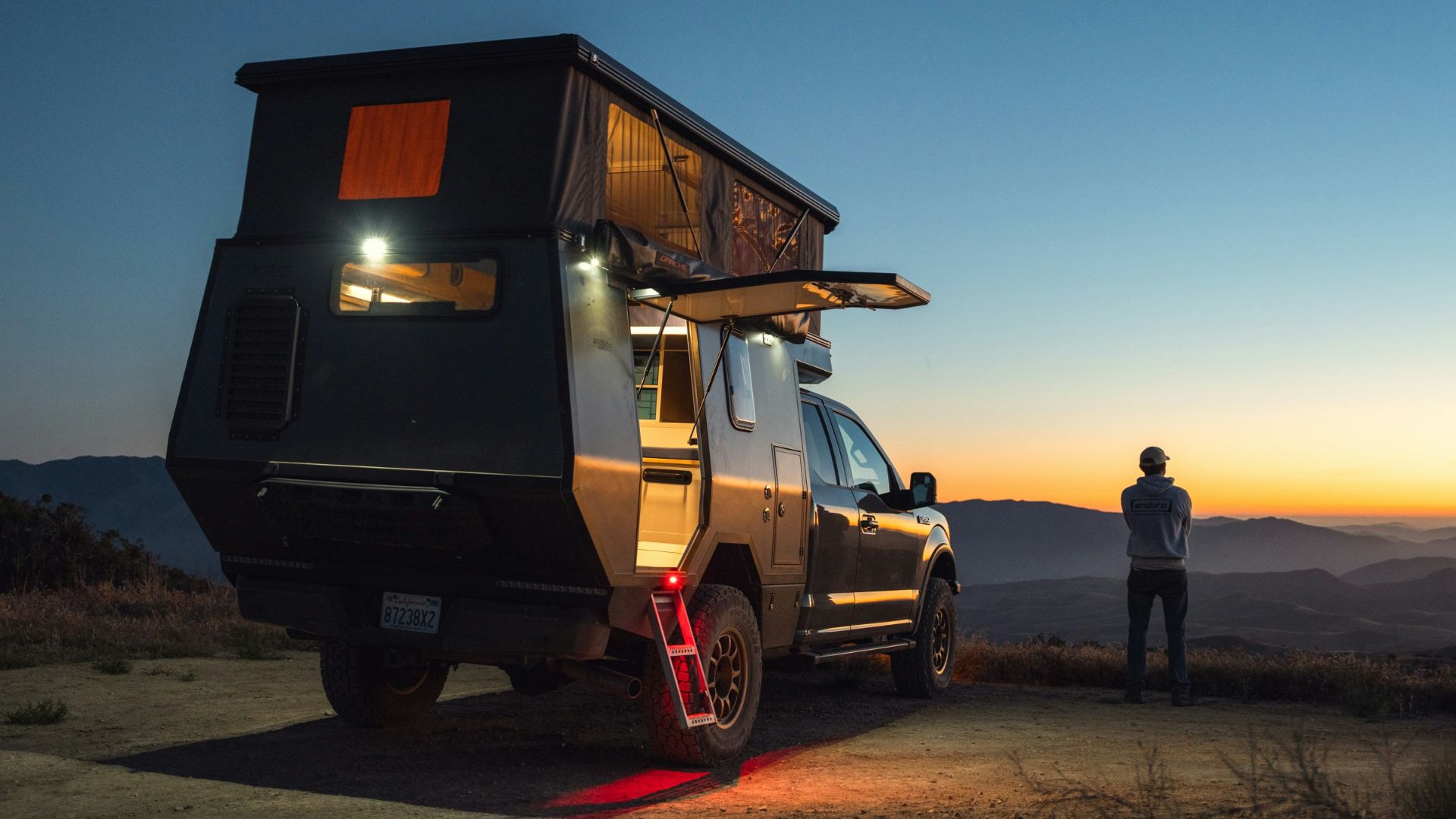 a man standing next to a truck with a camper on it