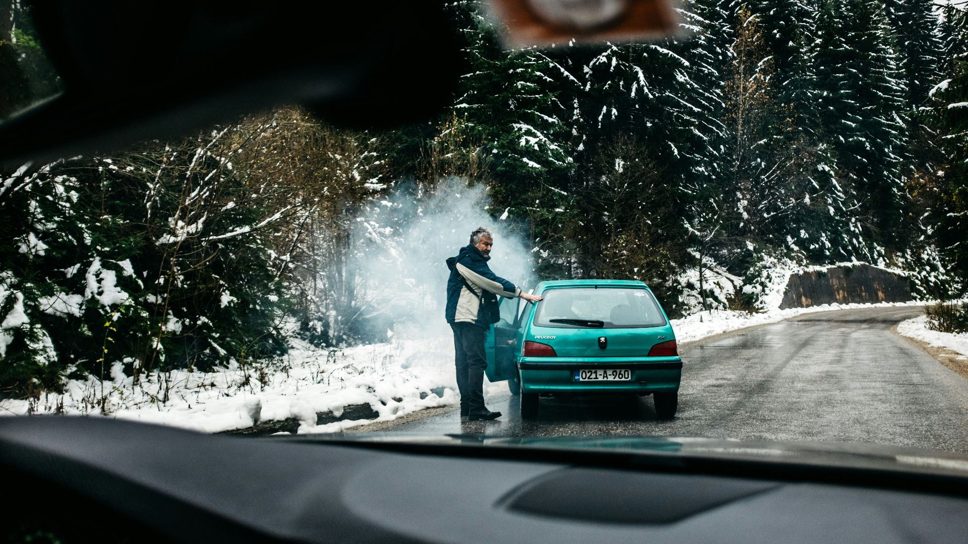 man standing in front of teal vehicle hatchback