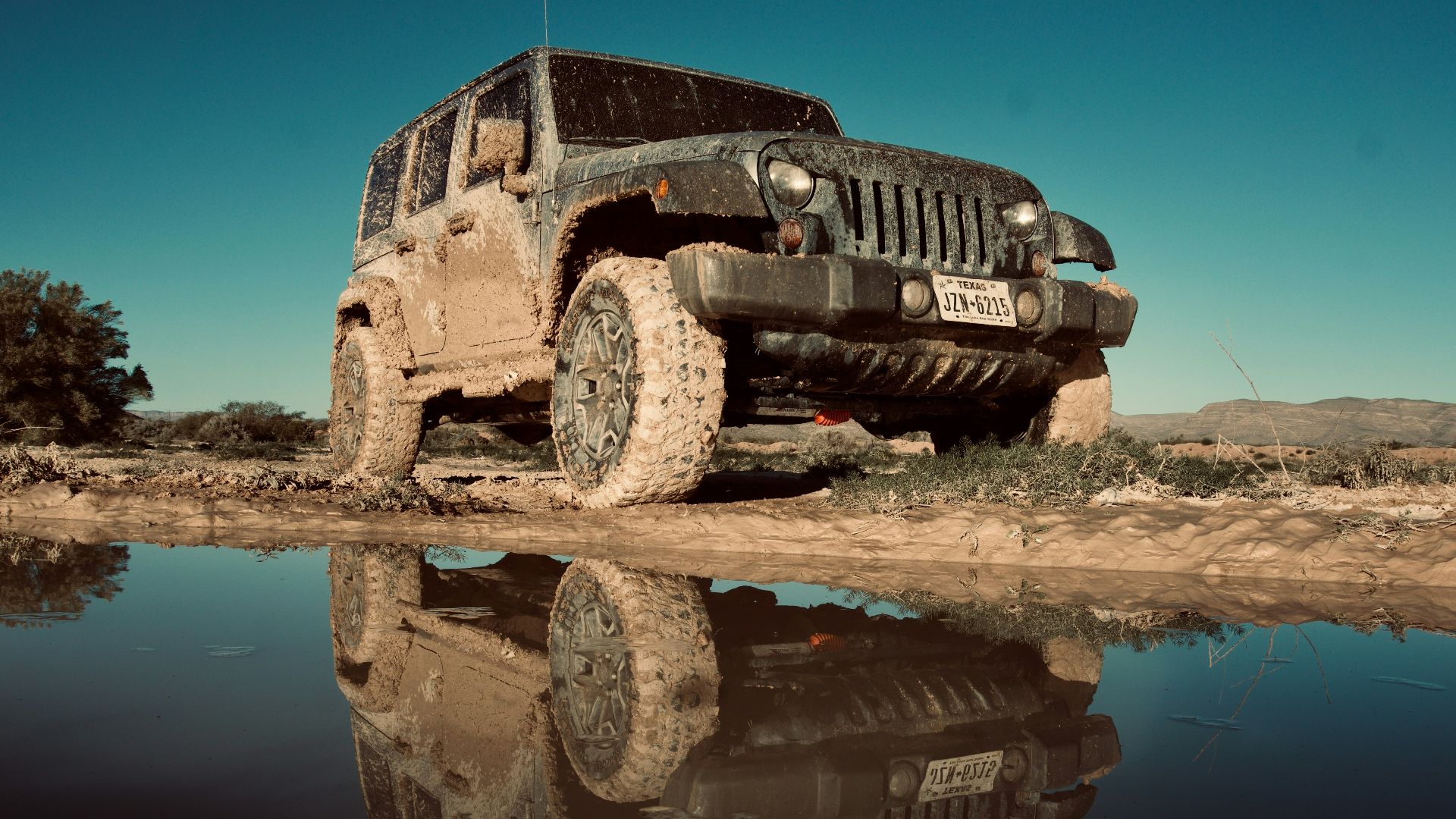 black Jeep Wrangler Unlimited SUV parked near body of water under clear sky at daytime