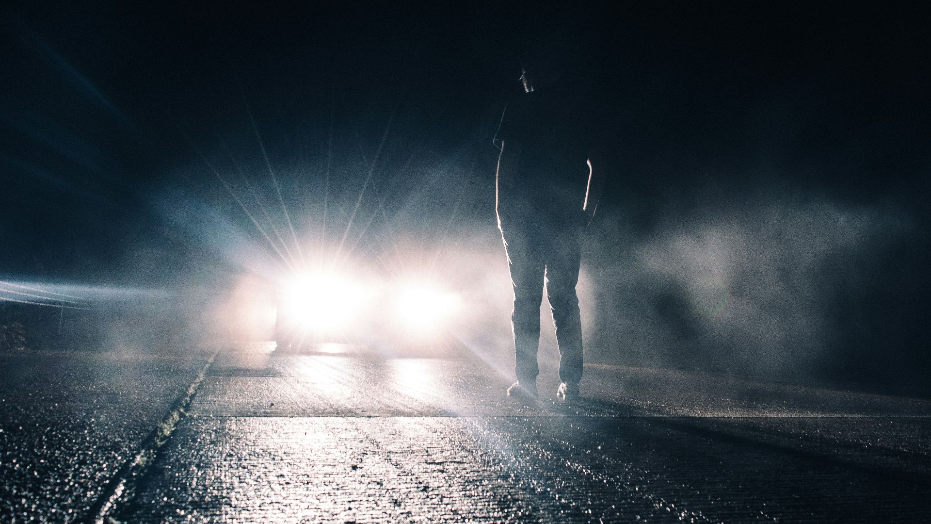man standing in front of lighted car