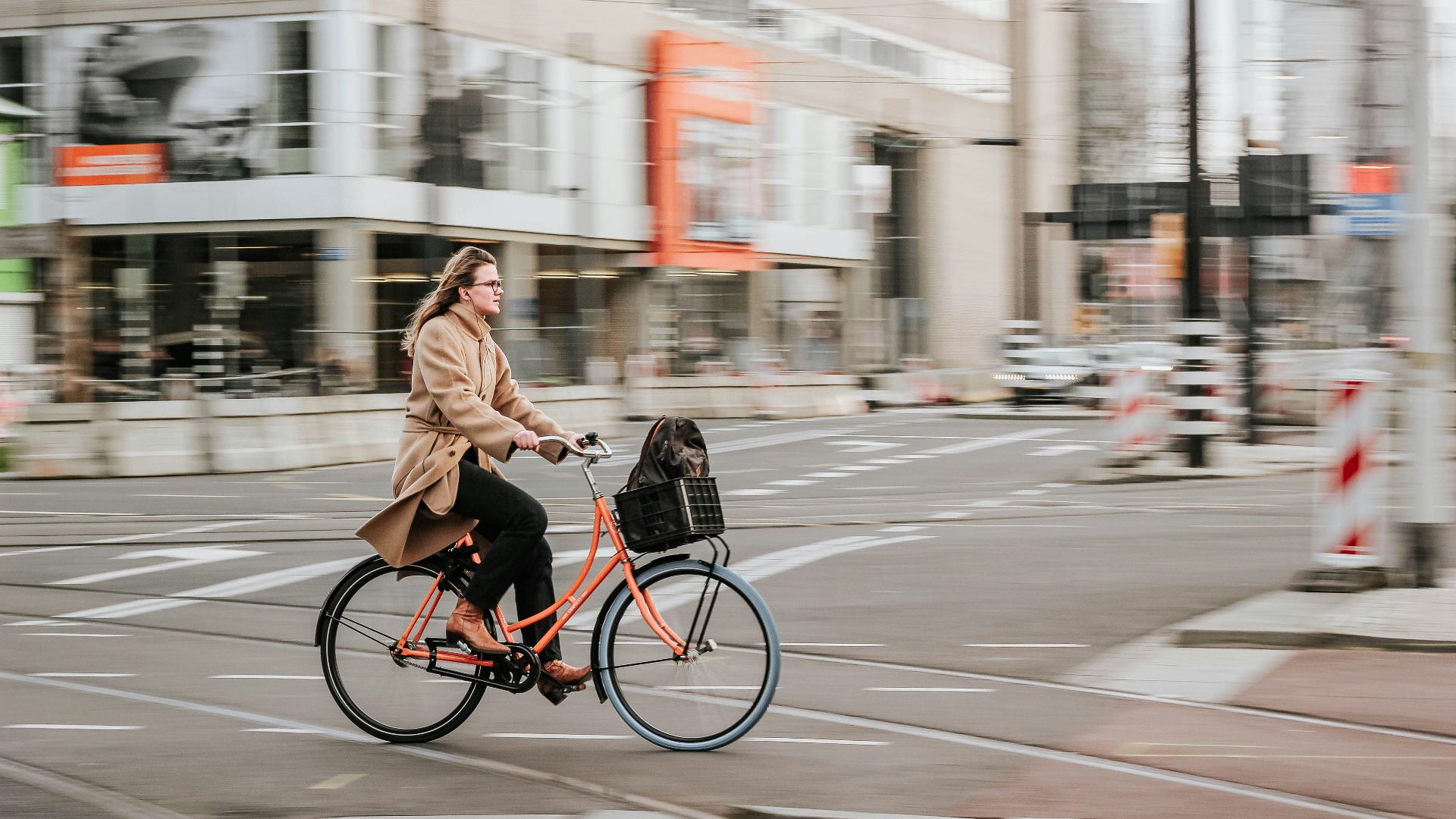 woman in brown coat riding on black bicycle on road during daytime