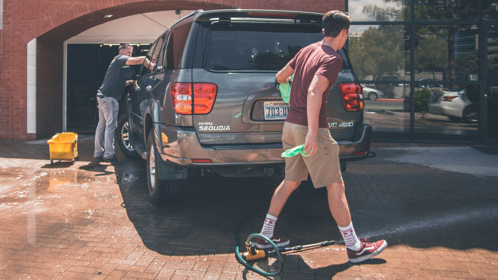 man cleaning silver SUV