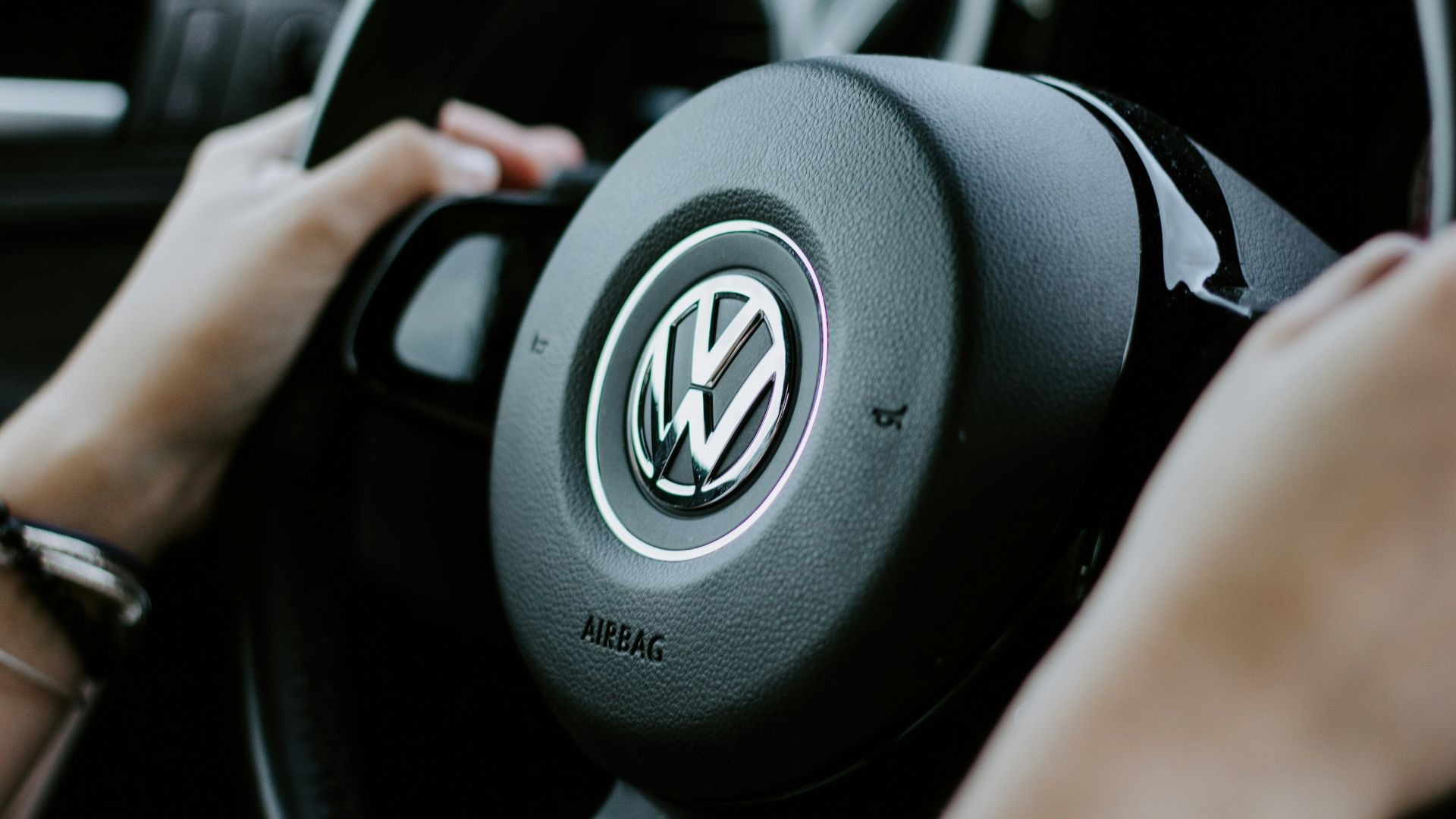 person holding black Volkswagen steering wheel in closed-up photo