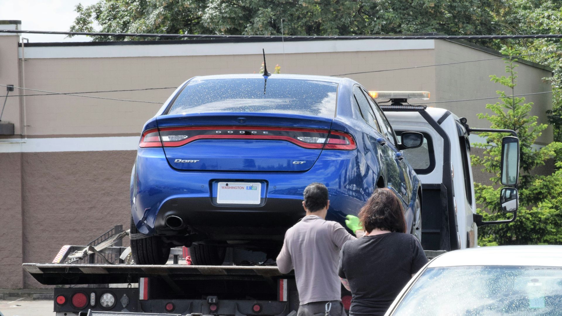 a blue car being loaded onto a flatbed truck