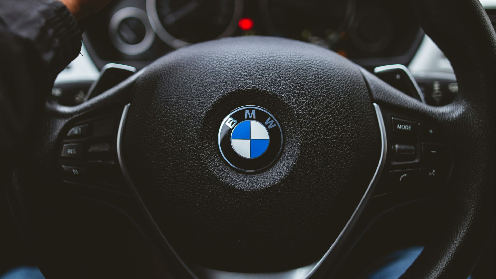 person holding BMW vehicle steering wheel