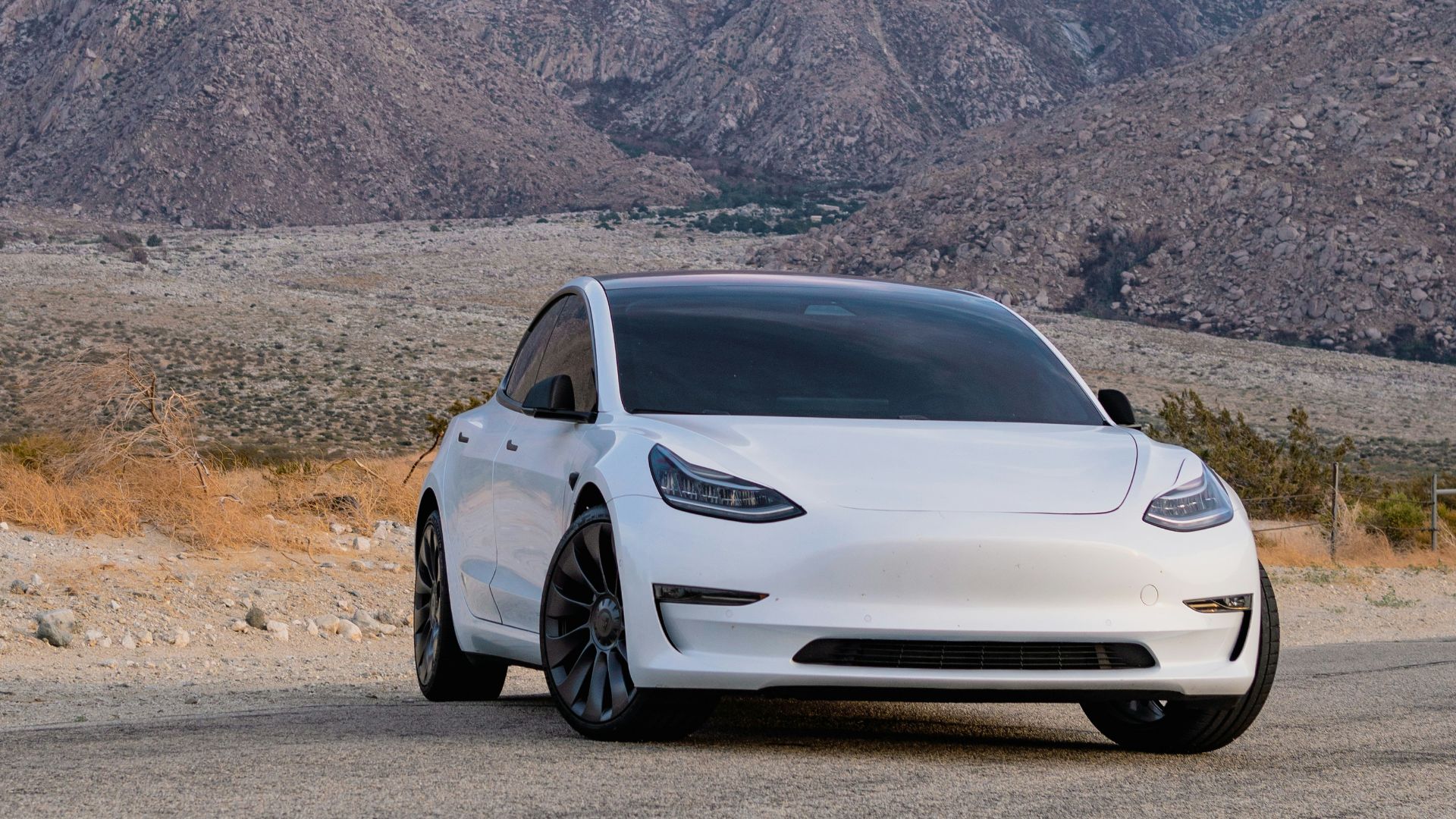 a white car parked in front of a mountain range