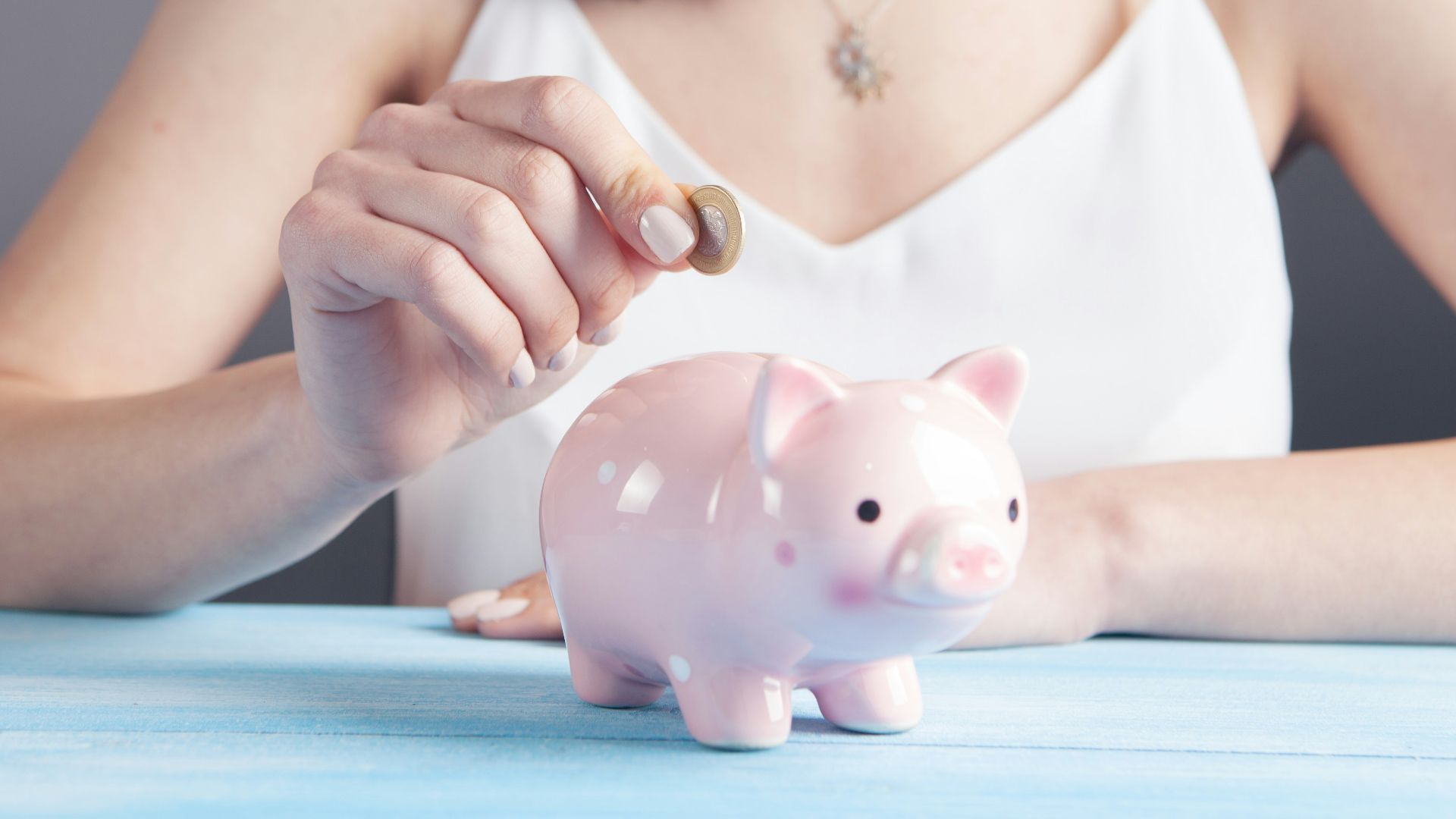 woman in white tank top holding pink pig figurine
